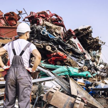 junkyard-worker-looking-large-pile-scrap-metal_Easy-Resize.com
